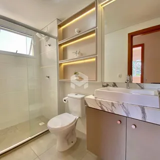 Banheiro com box de vidro, vaso sanitário e bancada de mármore.