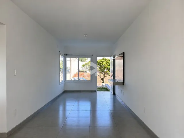 Hall de uma residência com paredes brancas e piso de cerâmica clara.