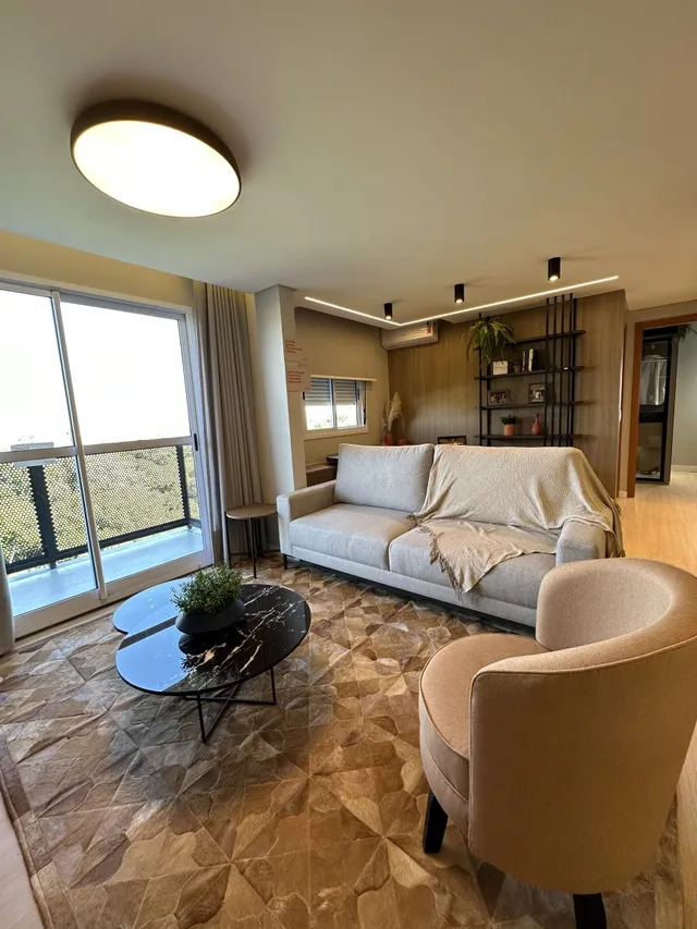Sala de estar com sofá e poltrona e grande janela.