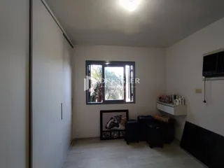 Interior de uma sala com piso de madeira clara e janela grande.