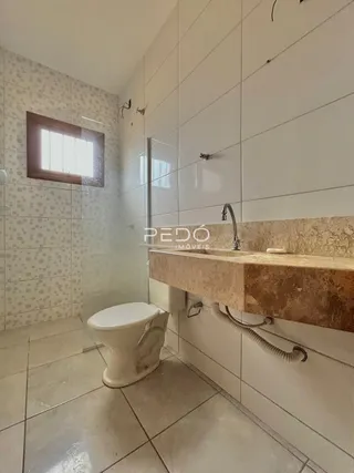 Foto de um banheiro com piso de cerâmica e azulejos brancos.