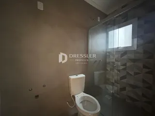Foto de um banheiro com revestimento cerâmico e box de vidro.