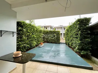 Vista de uma área externa com piscina e vegetação densa.