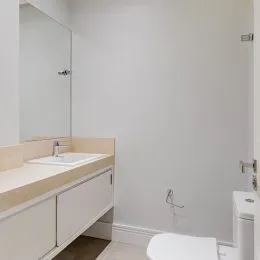 Foto de um banheiro interno mostrando uma bancada e pia brancas.