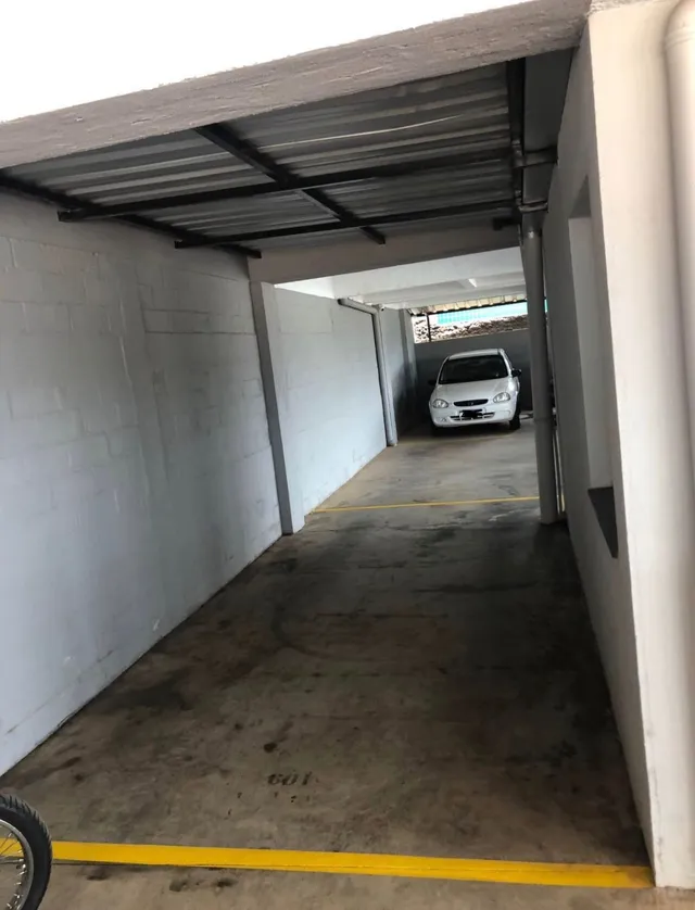 Vista interna de um pátio com piso de concreto e estrutura metálica.
