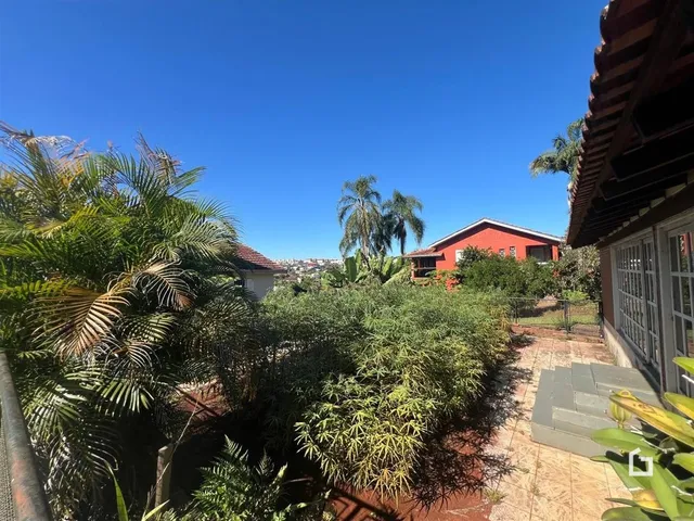 Vista externa de uma propriedade com vegetação exuberante sob um céu azul.