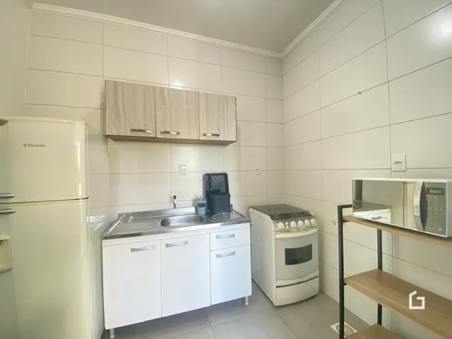 Foto de uma cozinha com armários brancos e revestimento de cerâmica.