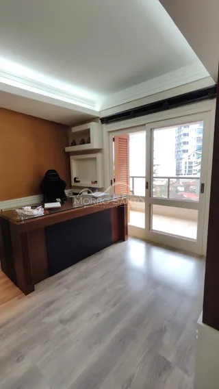 Ambiente interno com piso de madeira e acesso a uma porta de vidro com vista urbana.