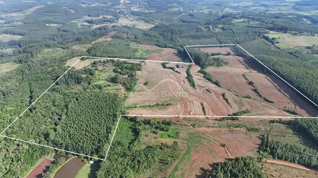 Vista aérea de uma propriedade rural com áreas de mata e campos cultivados.
