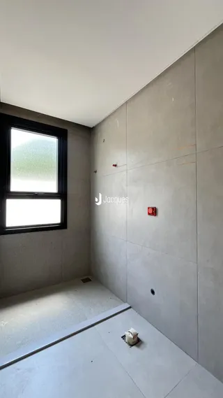 Vista interna de um ambiente com paredes de concreto aparente e piso liso.