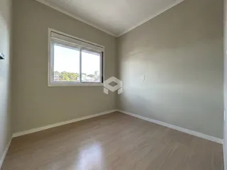 Vista interna de uma sala com piso de madeira e janela.