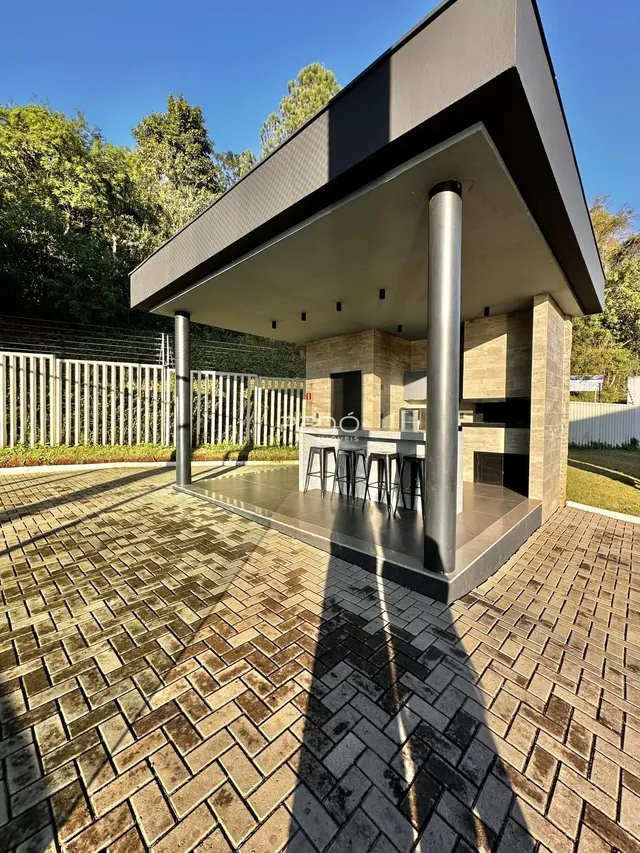 Vista da área externa com estrutura de pérgola e piso de tijolos.
