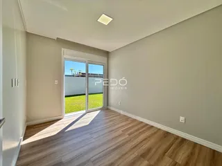 Ambiente interno de uma sala com piso de madeira e porta de vidro.