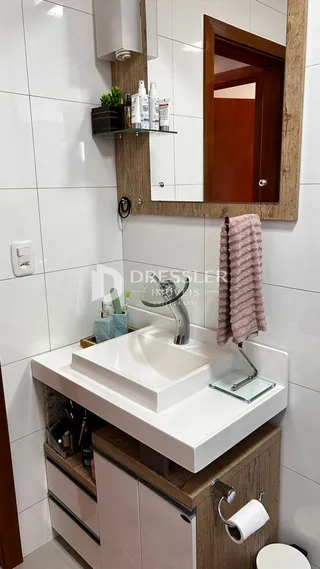 Foto de um banheiro moderno com bancada branca e armários de madeira.