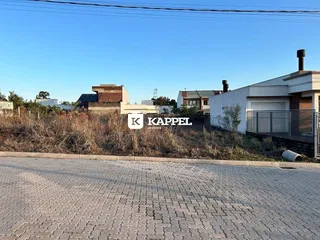 Vista externa de uma residência com vegetação seca ao fundo.