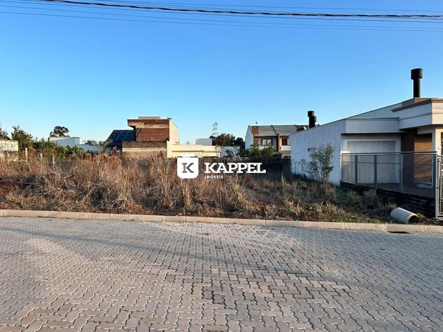 Vista externa de uma residência com vegetação seca ao fundo.