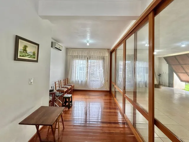 Interior de uma sala com piso de madeira e portas de vidro que dão acesso ao exterior.