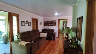Sala de estar com sofá marrom e piso de madeira em um imóvel em Lajeado.