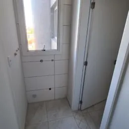 Hall de entrada com paredes brancas e armários brancos.