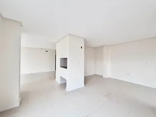 Sala ampla e branca com piso de cerâmica.