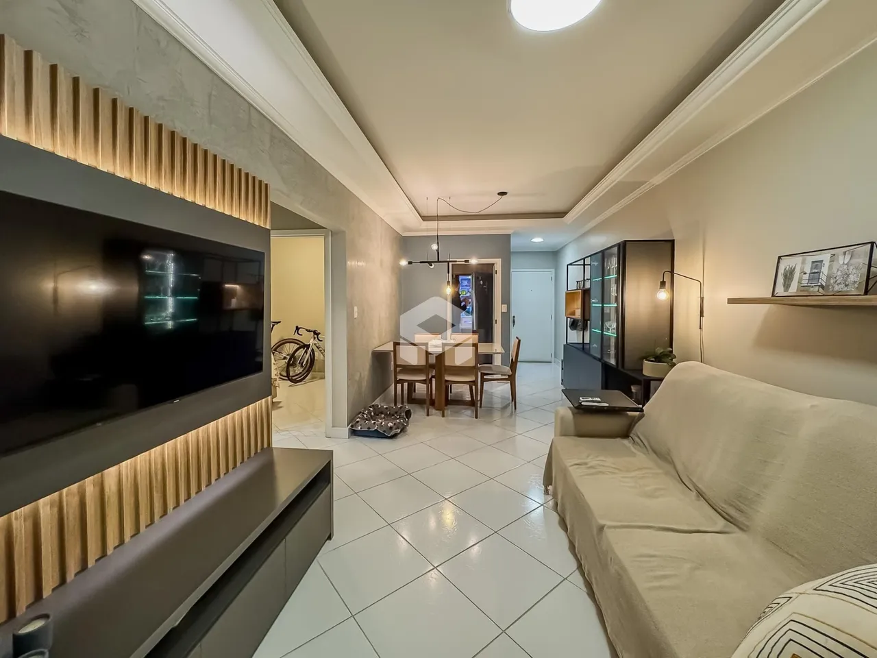 Sala de estar com televisão e área de passagem em um apartamento.