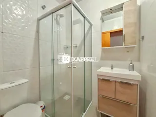 Banheiro com box de vidro e louças brancas.