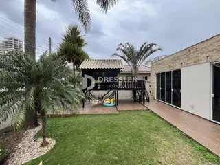 Vista da fachada de uma propriedade com jardim e palmeiras.