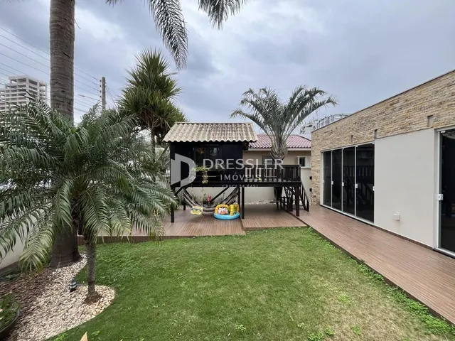 Vista da fachada de uma propriedade com jardim e palmeiras.