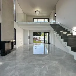 Hall de entrada com piso claro e escadaria em um apartamento.