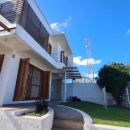 Fachada de uma residência branca com jardim e estrutura moderna.