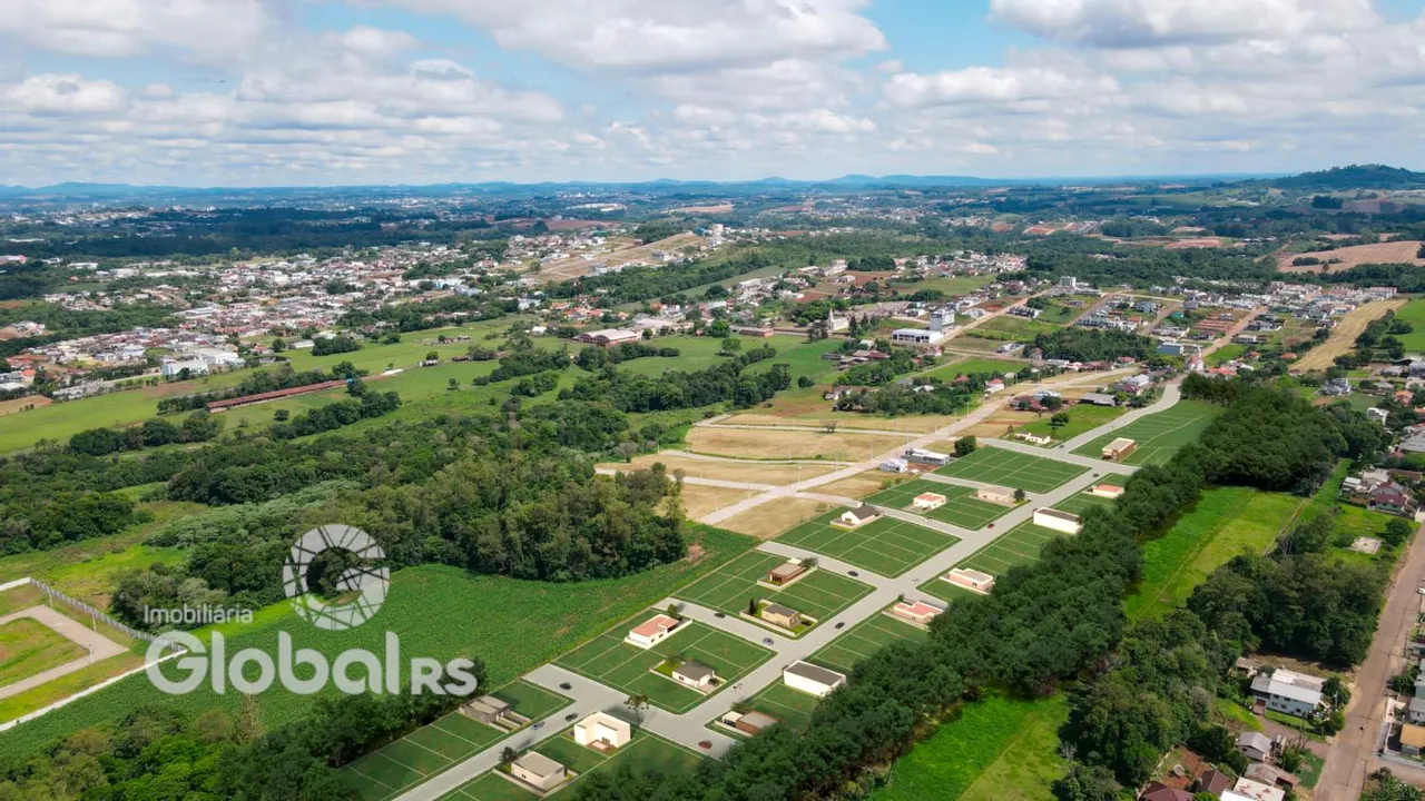 Vista aérea de uma área residencial com campos e vegetação no Brasil.