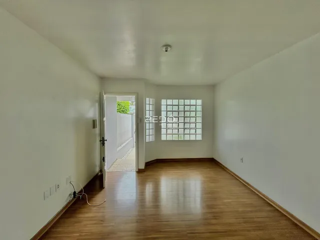 Sala de estar com piso de madeira e paredes brancas.