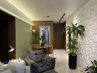 Sala de estar com sofá cinza, mesa de jantar de madeira e plantas decorativas.