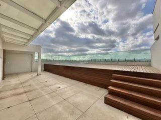 Vista de uma área externa com deck de madeira e piso de concreto.
