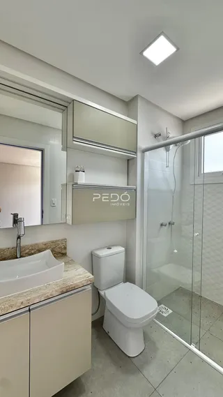 Banheiro moderno com box de vidro e revestimento de cerâmica.