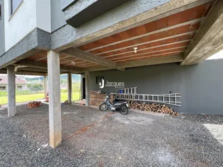 Vista externa de uma estrutura de prédio com pilares de concreto e telhado de telhas.