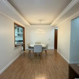 Foto interna de um ambiente com piso de madeira e mesa de jantar.