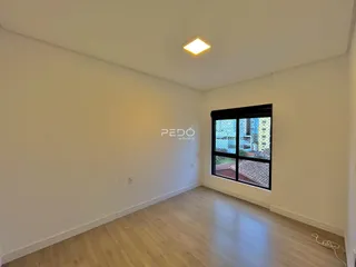 Ambiente interno de uma sala com piso de madeira clara e janela.
