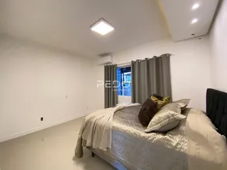 Quarto com cama e cortinas cinzas em um imóvel.