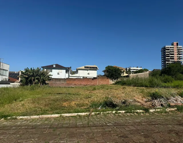 Vista externa mostrando casas baixas e um prédio alto sob um céu azul claro.