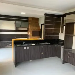 Interior de uma cozinha com armários escuros e acabamento em madeira escura.