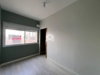 Ambiente interno de uma sala com piso de madeira clara e parede cinza.