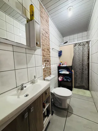 Banheiro com revestimento de cerâmica branca e parede de tijolo aparente.