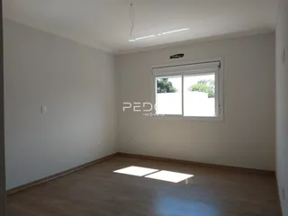 Quarto vazio com piso de madeira clara e janela.
