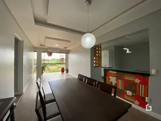 Ambiente interno com mesa de jantar e vista para o exterior.
