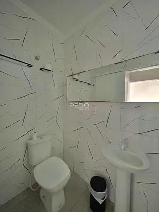 Banheiro com revestimento de mármore nas paredes e piso claro.
