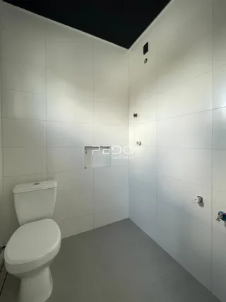 Foto de um banheiro com paredes brancas e piso claro.
