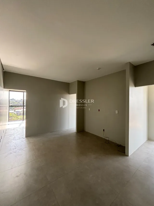 Vista interna de um ambiente com paredes lisas e piso de concreto.