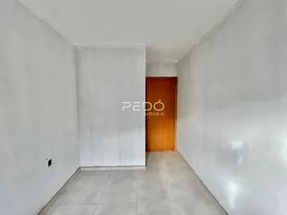 Hall de entrada com paredes brancas e piso de cerâmica clara.