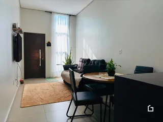 Sala de estar com sofá e mesa de jantar em ambiente claro.